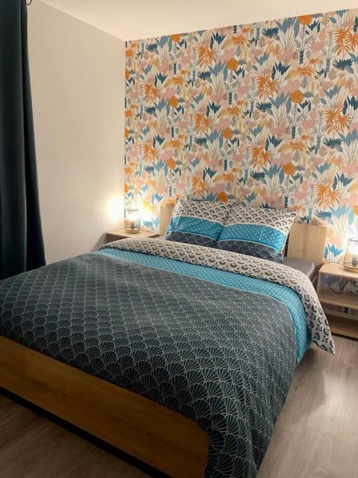 - une chambre avec un grand lit et du papier peint floral dans l'établissement Chez Lyseha et André, à Saint-Claude