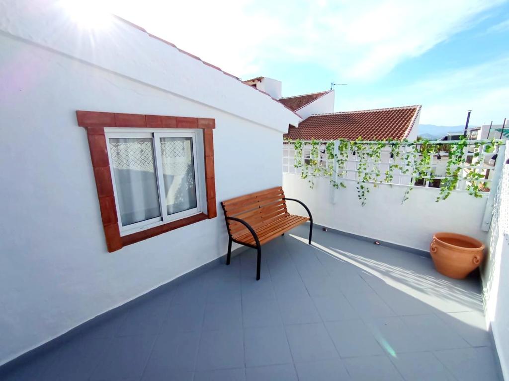 a bench sitting on a balcony with a window at Red House in Alhaurín el Grande