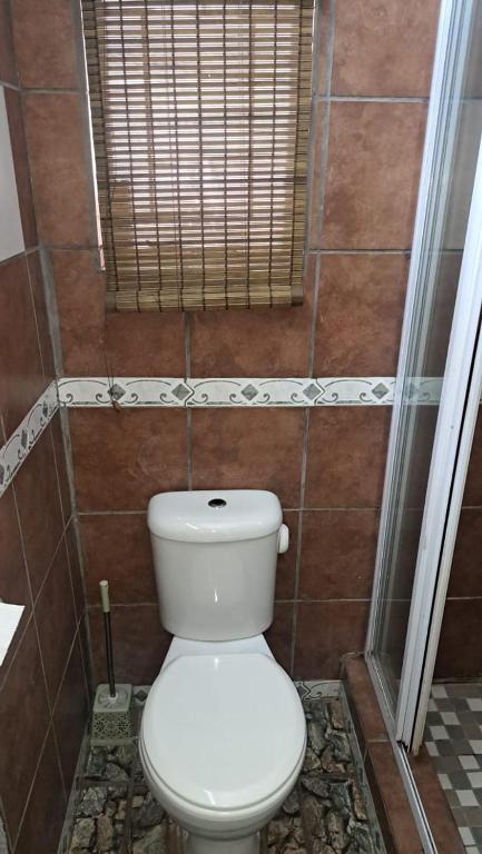 aseo blanco en un baño con ventana en At Home Guest House, en Postmasburg