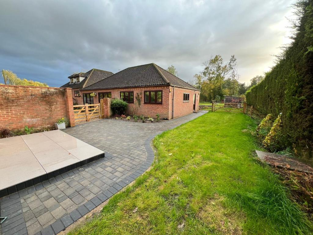 a brick house with a patio and a yard at Little Edgewood in Norwich