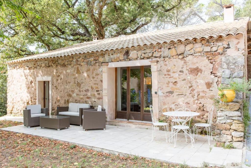 Cette maison en pierre dispose d'une terrasse, d'une table et de chaises. dans l'établissement La bergerie des pins, à La Roquette-sur-Siagne