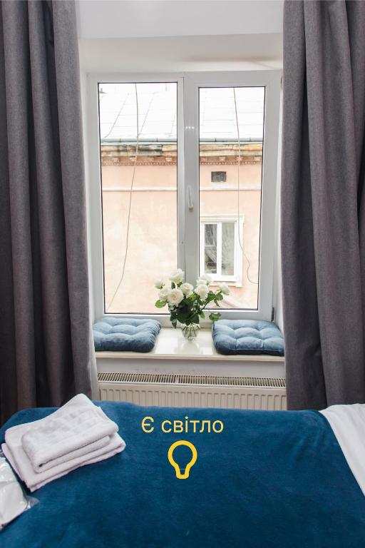 a room with a window with a blue bed and a vase of flowers at Mary in Lviv