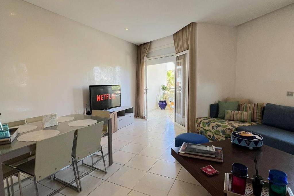 a living room with a couch and a table and a tv at Appartement Bahia Golf Beach Bouznika,Plage & Golf in Bouznika