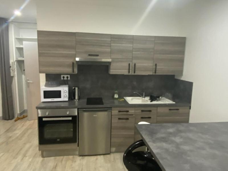 une cuisine avec des placards en acier inoxydable et un four micro-ondes dans l'établissement Le onze, à Lons-le-Saunier