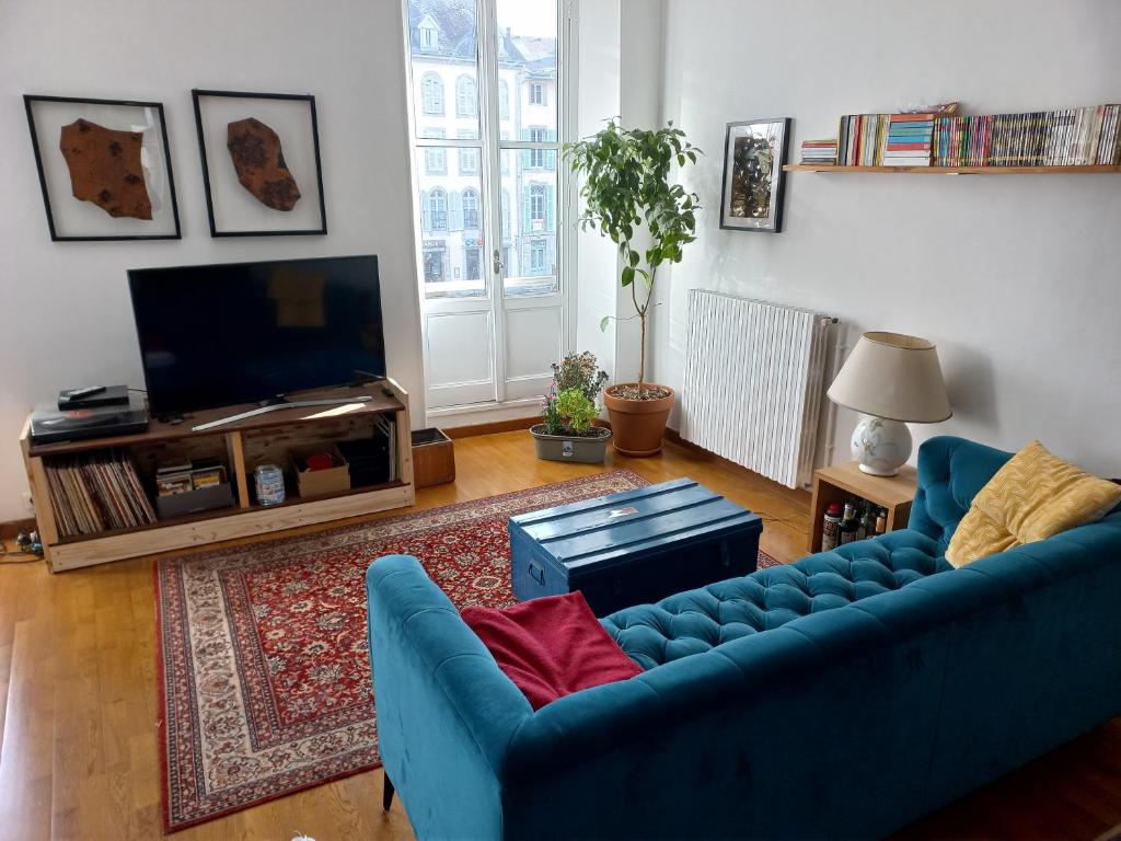 un salon avec un canapé bleu et une télévision dans l'établissement Les Coustous, à Bagnères-de-Bigorre