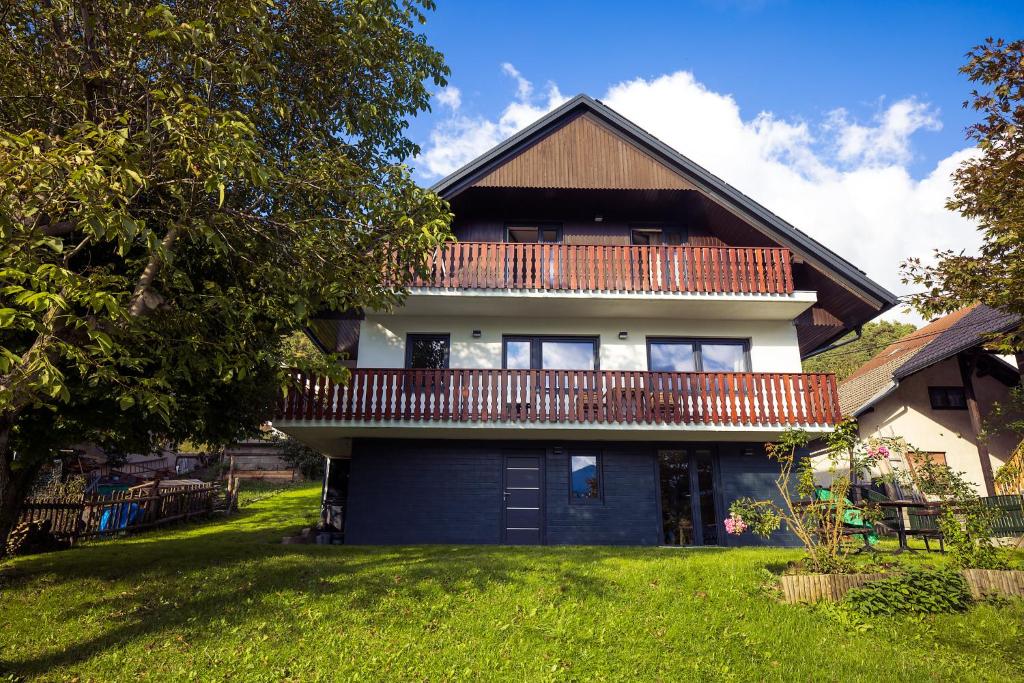 a house with a deck on top of a yard at Via Alpina Apartments with sauna in Mojstrana