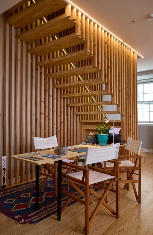 a dining room with a table and chairs and wooden stairs at Matriz 55 in Ponta Delgada