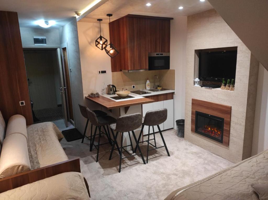 a kitchen with a bar and a fireplace in a room at Apartmani Iva Kop Konaci in Kopaonik