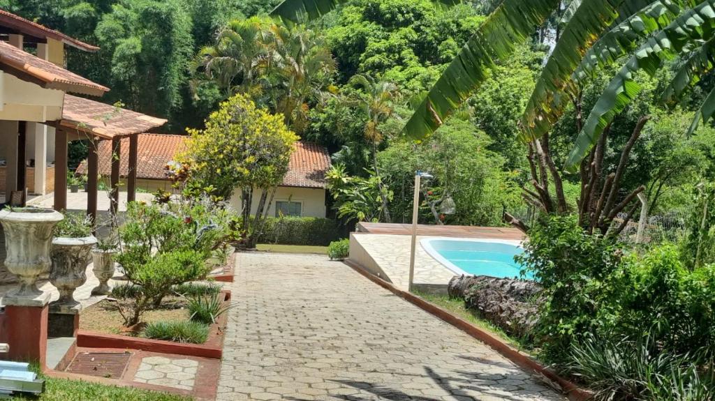 a garden with a swimming pool and a house at Flor de Jabuticabeira in Jaguariúna
