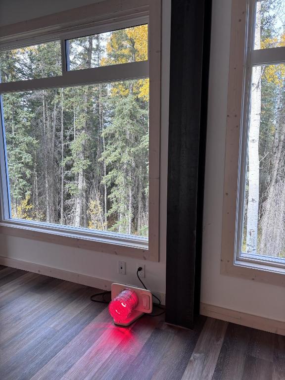 a room with two windows and a red object on the floor at Jasper East Hostel - Near Jasper National Park East Gate Entrance in Jasper