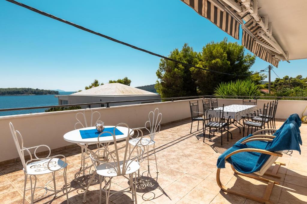 a patio with tables and chairs on a balcony at Apartments by the sea Cove Nova, Korcula - 11353 in Vela Luka