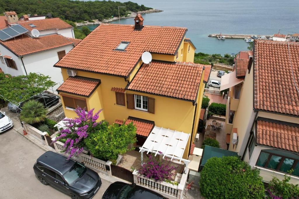 a yellow house with a man sitting on the roof at Apartments with a parking space Mali Losinj (Losinj) - 15201 in Mali Lošinj
