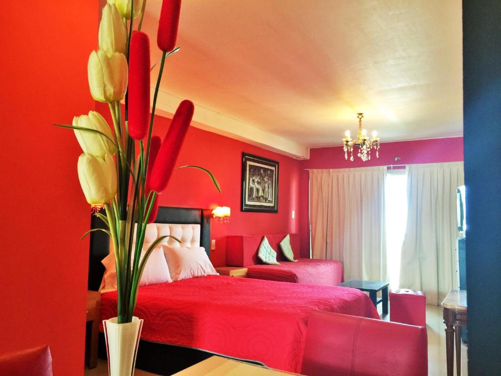 un dormitorio rojo con una cama y un jarrón de flores en Departamentos Sobre el Mar en Villa Gesell