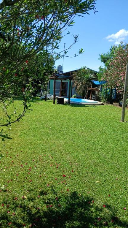 a green yard with a house in the background at Cabaña Madreselva in Colonia Benítez