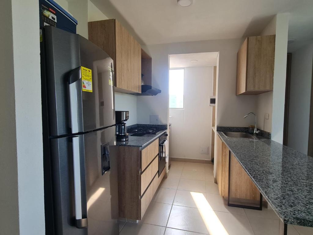 Una cocina con refrigerador de acero inoxidable y gabinetes de madera. en Conjunto Bello Horizonte Plaza, en Santa Marta
