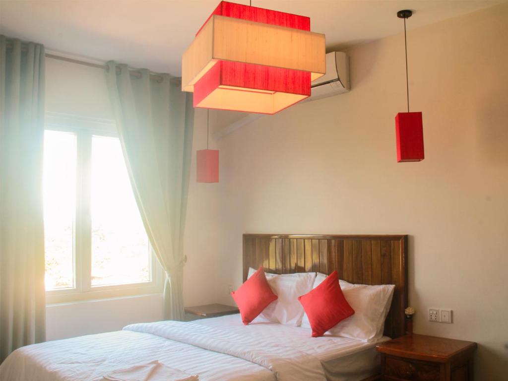 Un dormitorio con una cama con almohadas rojas y una lámpara de araña. en Sokha Home en Bahal