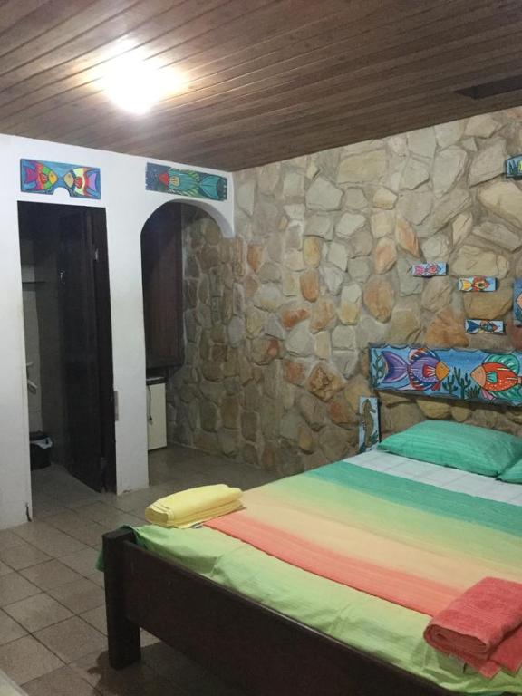 1 dormitorio con 1 cama y pared de piedra en Pousada Alquimia en Olinda