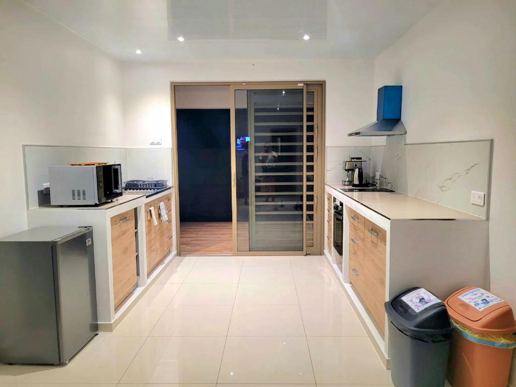 a large kitchen with white counters and appliances at Logement de charme, au soleil et proche de la mer in Moorea