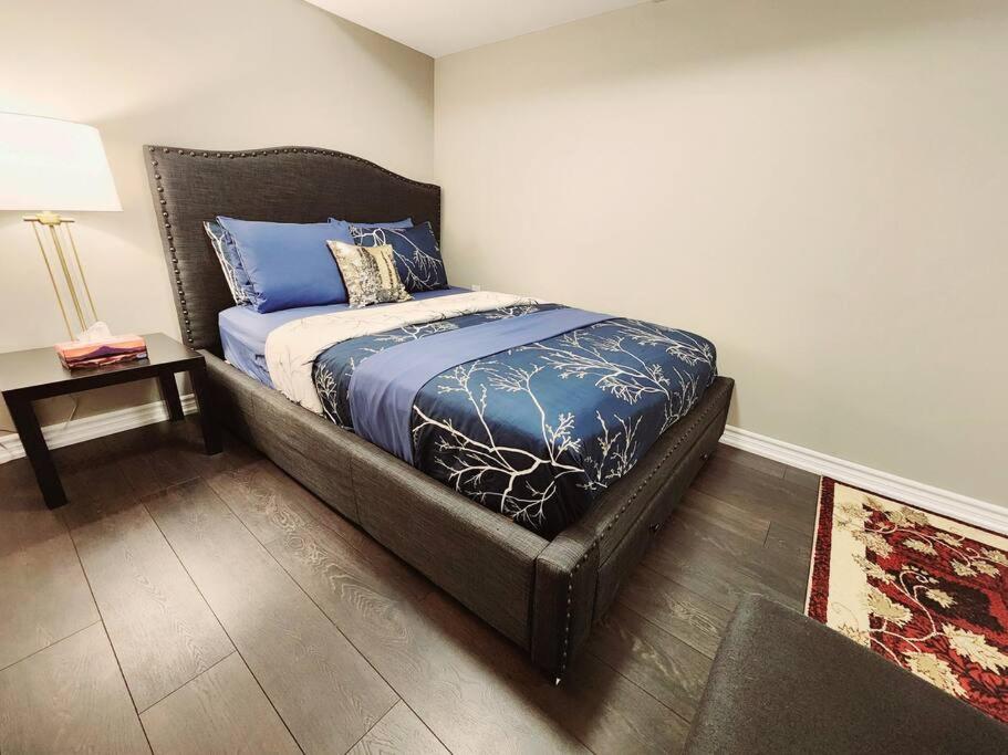 a bedroom with a bed with blue sheets and a table at 1 Bedroom basement apartment with separate entrance in Milton