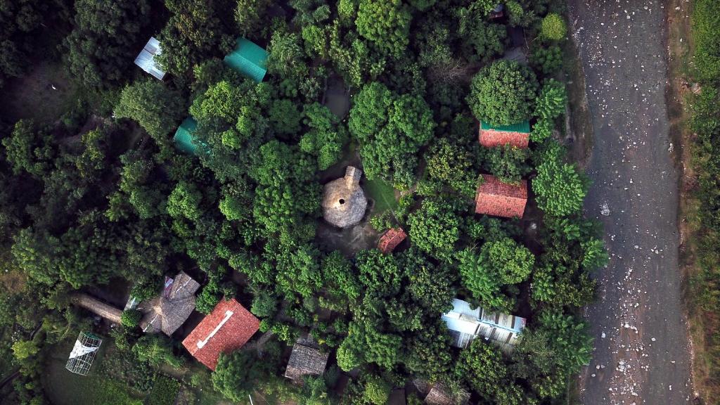 an overhead view of a forest with houses and a road at Camp Hornbill Corbett in Rāmnagar