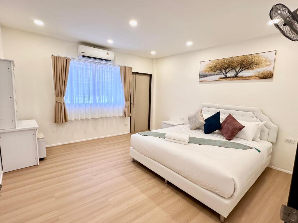a bedroom with a white bed and a window at Peace Homestay Hat Yai in Hat Yai