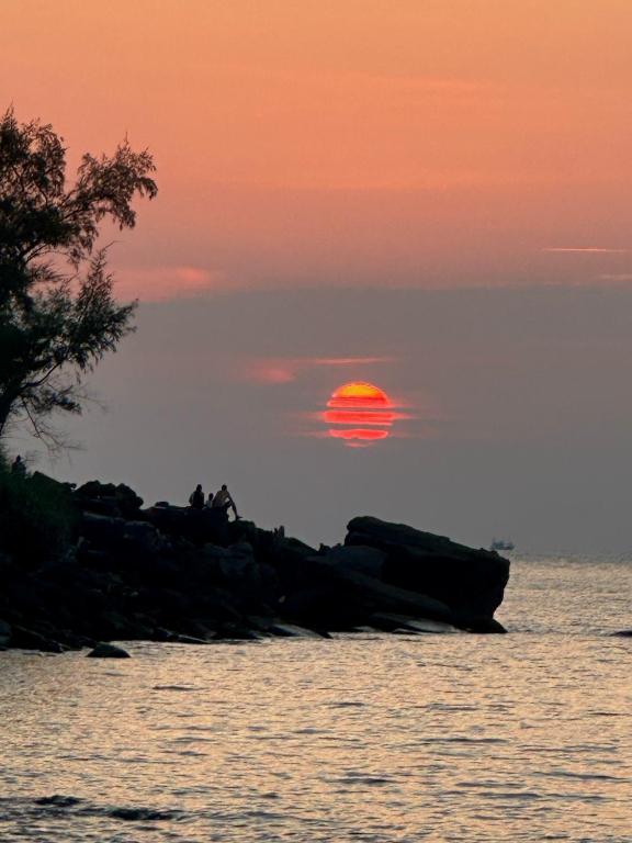 two people sitting on rocks in front of the ocean at sunset at Lazy Bones in Koh Rong Sanloem