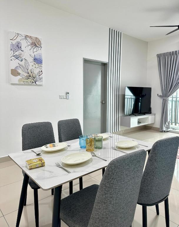 a white dining room table with chairs and a television at Bayu Temiang Homestay in Seremban