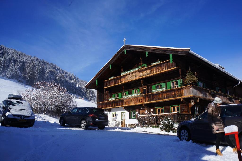 ein großes Holzgebäude mit Autos im Schnee in der Unterkunft MyApart 1709 in Jochberg