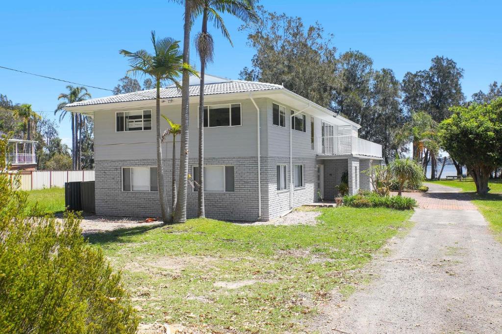 a white house with palm trees and a driveway at Sanctuary Bliss in Sanctuary Point