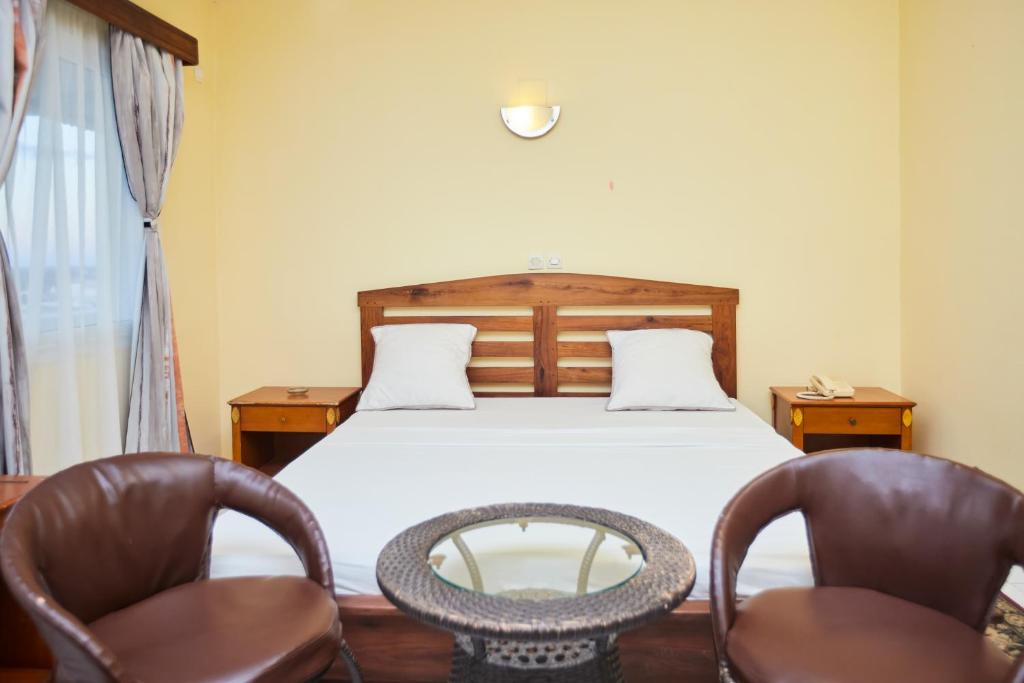 a bedroom with a bed and two chairs at Anjary Hotel Mahajanga in Mahajanga