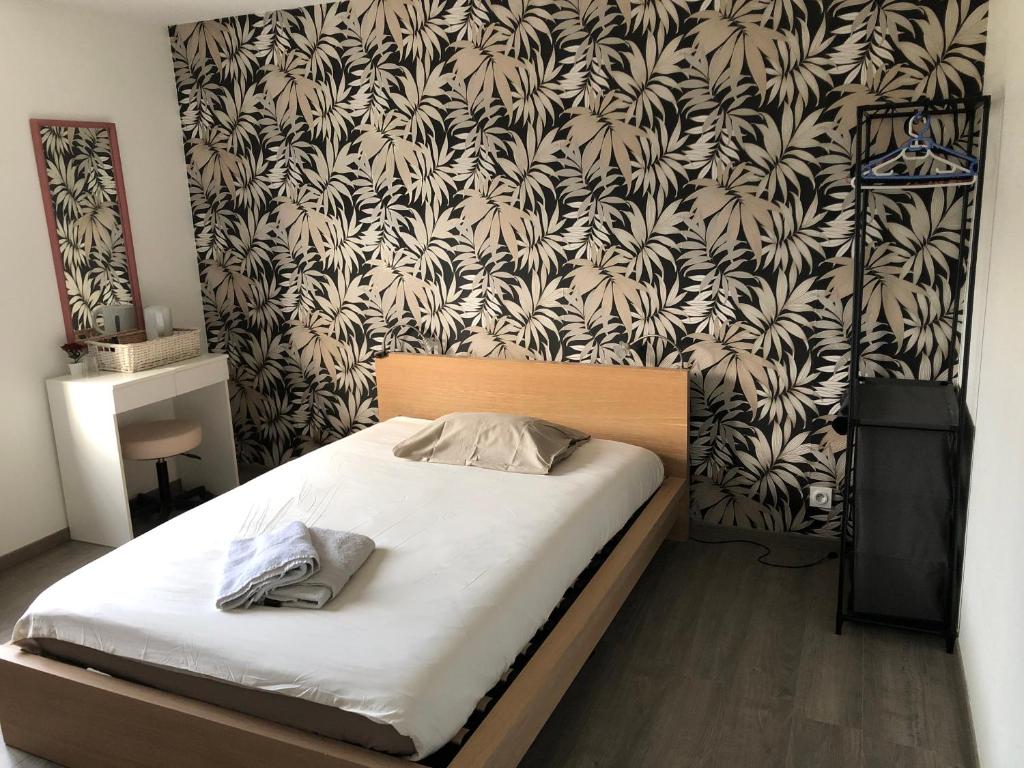 a bed in a bedroom with a black and white wallpaper at Grande chambre côté jardin in Château-du-Loir
