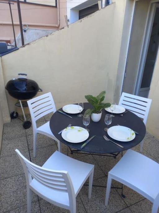 une table et des chaises noires avec des assiettes et une plante sur celle-ci, dans l'établissement Maison à 50 m de la plage, à Banyuls-sur-Mer