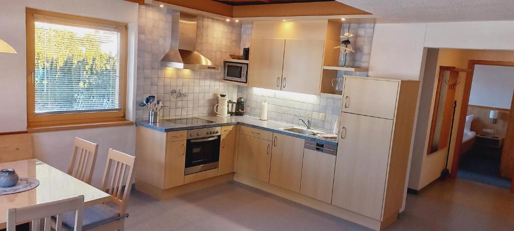 a kitchen with a white refrigerator and a table with a tableablish at Apartments RIFA - Gaschurn in Gaschurn