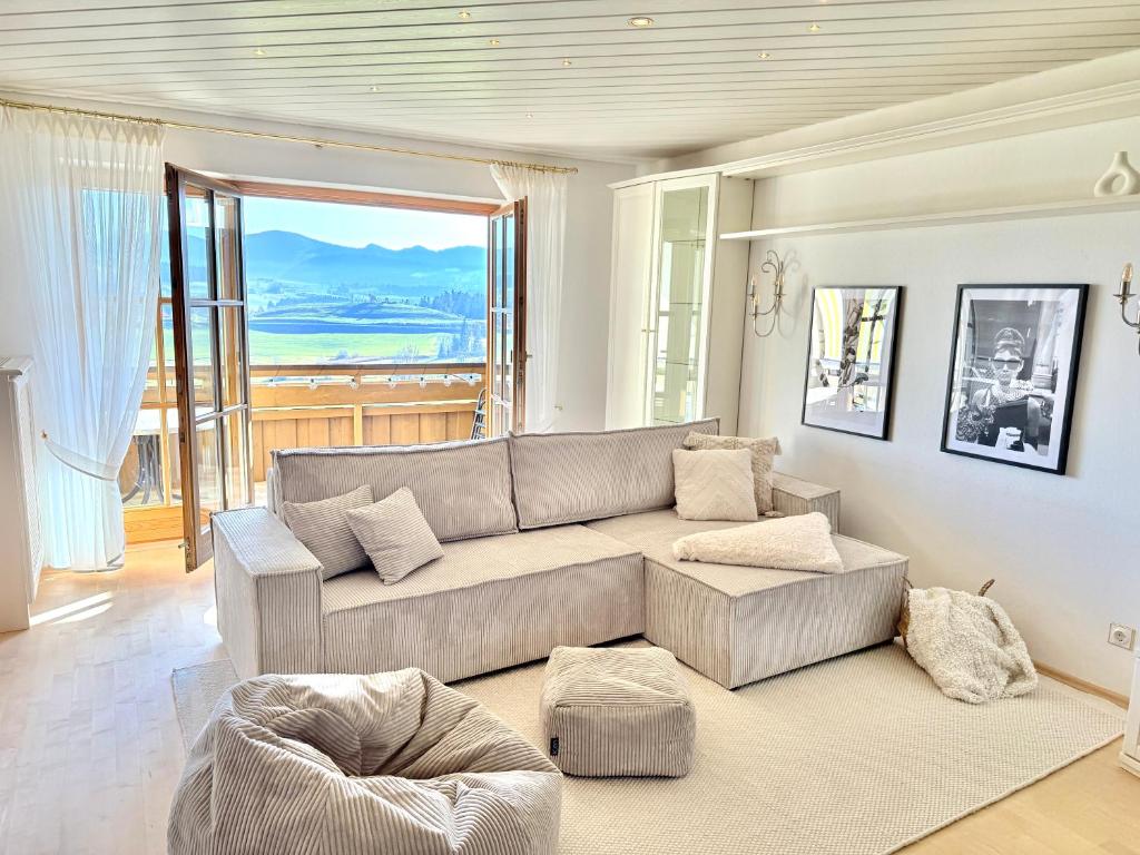 a living room with a couch and a large window at LOFTI'S Alpin View Suite in Oberreute