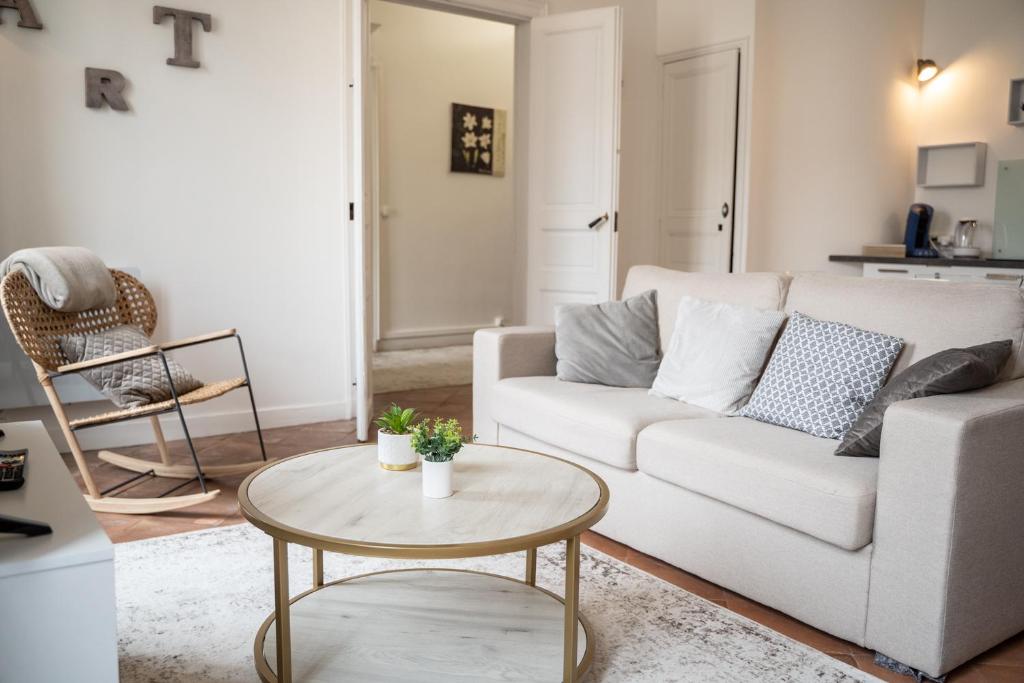 a living room with a white couch and a table at CHIC ANDREOSSY-COSY-AUTHENTIQUE-WI-Fi-Vélo in Castelnaudary