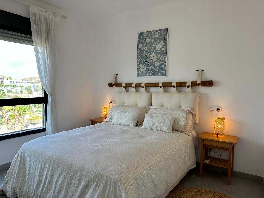 ein Schlafzimmer mit einem weißen Bett mit zwei Lampen und einem Fenster in der Unterkunft ViveVera - Chalet Palmera Golf Valle del Este in Vera