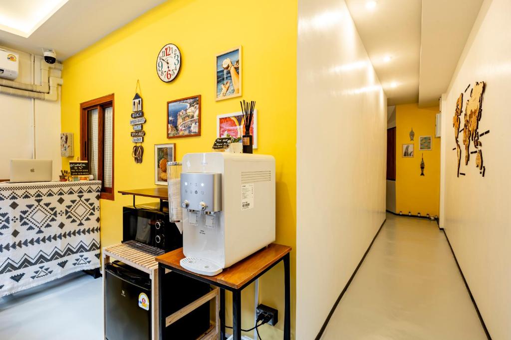 a room with yellow walls and a computer on a table at Sweett Lemon Hostel in Patong Beach