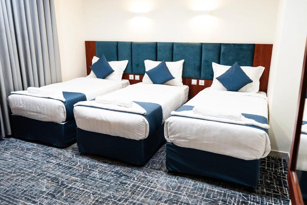 a bedroom with two beds with blue pillows at ديار المروة in An Naqāʼ