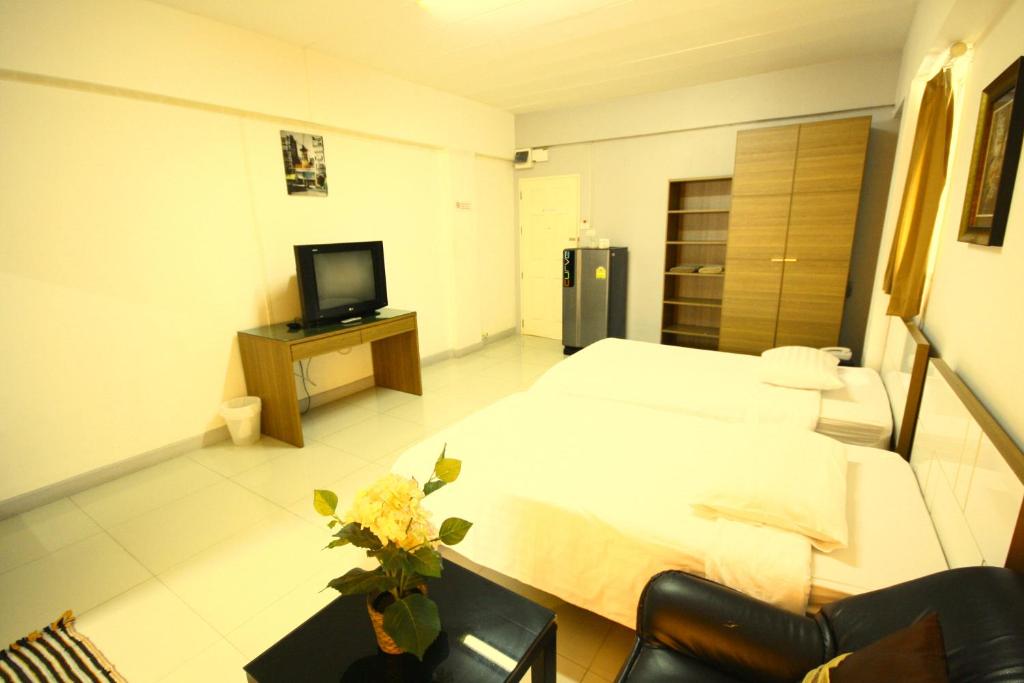 ein Hotelzimmer mit einem Bett und einem TV in der Unterkunft At Home Phetkasem in Bangkok