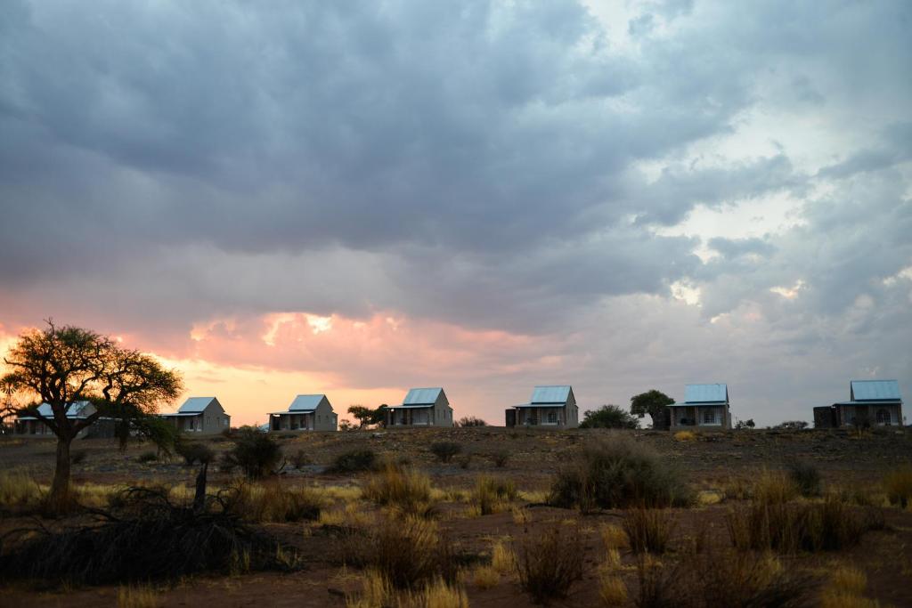 a group of houses in the desert under a cloudy sky at Alte Kalkoefen Lodge in Simplon
