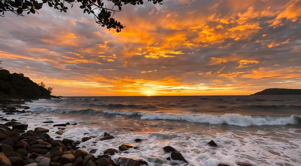 a sunset over the ocean with rocks on a beach at Lazy Bones in Koh Rong Sanloem