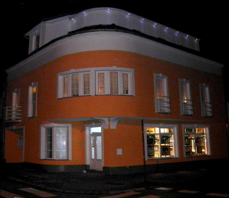 a large orange building with white windows at night at Villa Lucia - Apartments&Rooms in Slavonski Brod