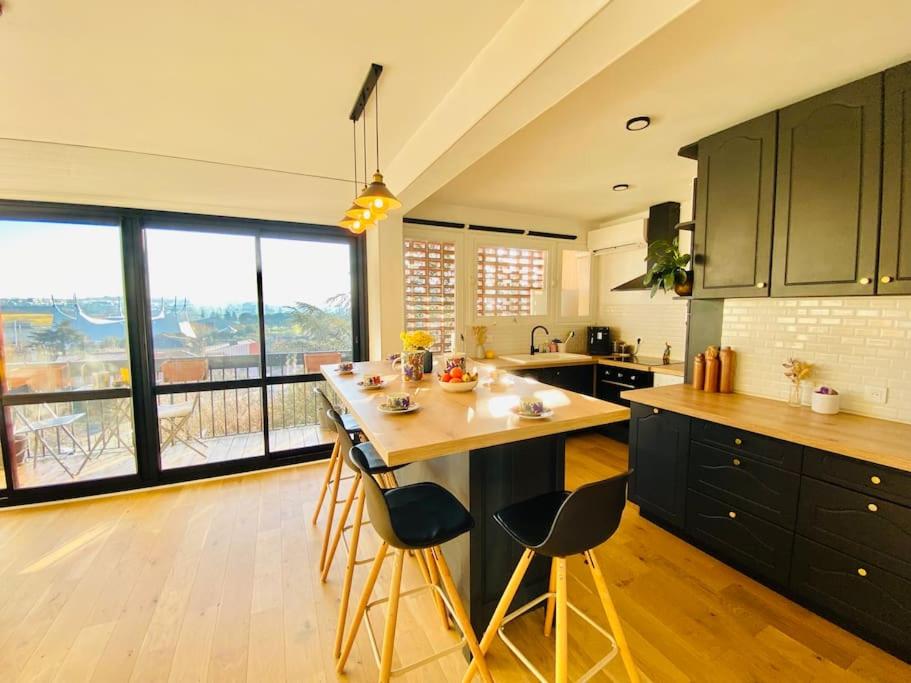 une cuisine avec des armoires noires et une grande fenêtre dans l'établissement Appart lumineux 2 chambres - quartier calme au pied du métro, à Toulouse