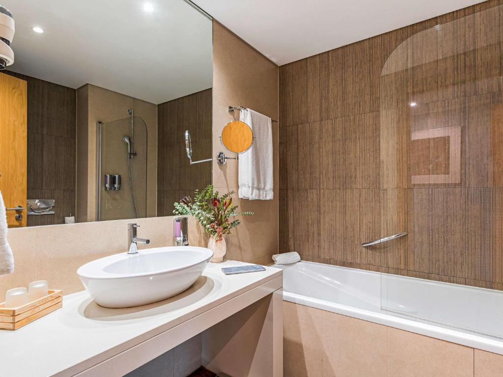a bathroom with a sink and a bath tub and a sink at Mercure Lisboa Almada in Almada