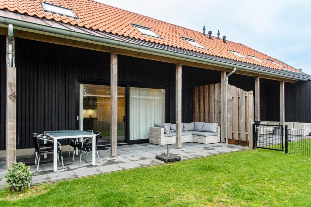 a patio with a table and a couch at De Plevieren in Buren