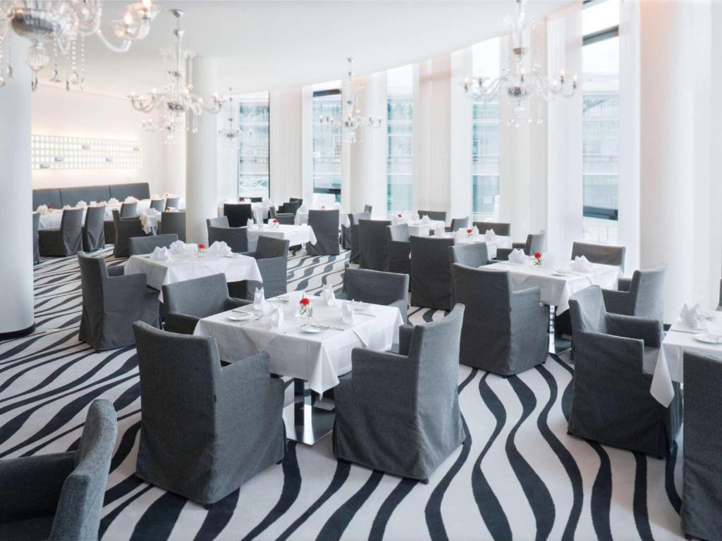 a dining room with white tables and chairs at Mövenpick Hotel Stuttgart Airport in Stuttgart