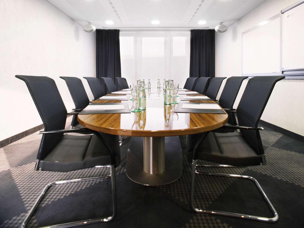 a conference room with a wooden table and black chairs at Mövenpick Hotel Stuttgart Airport in Stuttgart