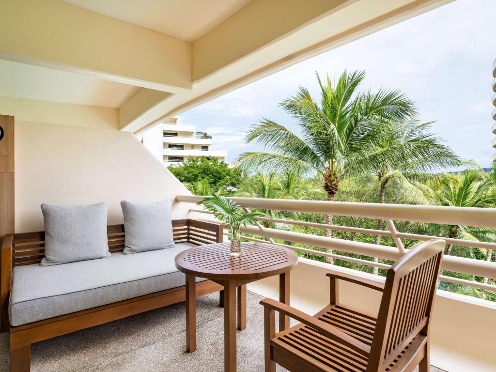 a balcony with a couch and a table and chairs at Pullman Phuket Karon Beach Resort in Karon Beach