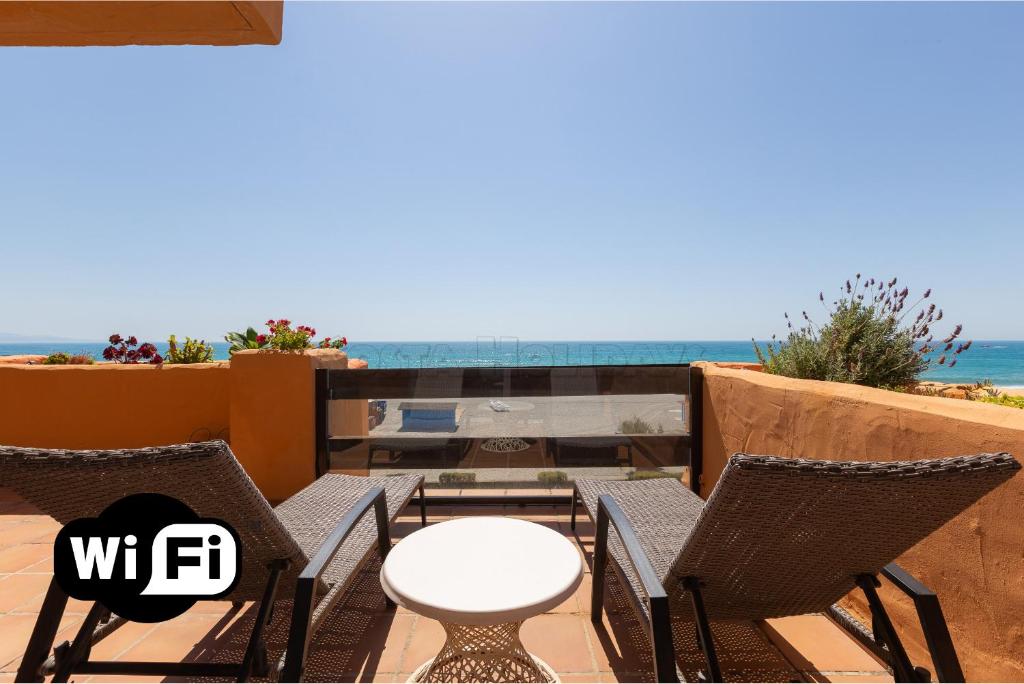 a patio with chairs and a table and the ocean at los granados 1221 in Manilva