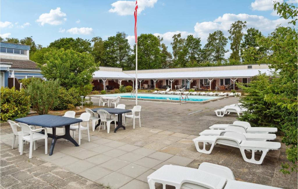 un patio avec tables et chaises à côté d'une piscine dans l'établissement Beautiful Apartment In Nexø With Sauna, à Strandby Gårde